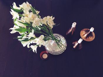 Close-up of white flowers in vase by candles on table