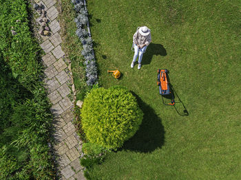 Woman with lawn mower sitting on chair in back yard