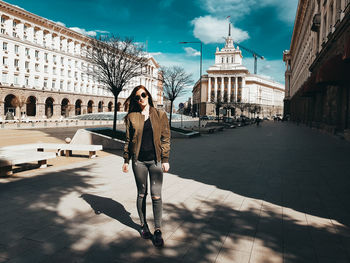 Woman with umbrella in city against sky