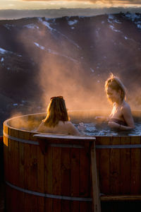 Two young women, friends, in barrels with hot water, sunset in n