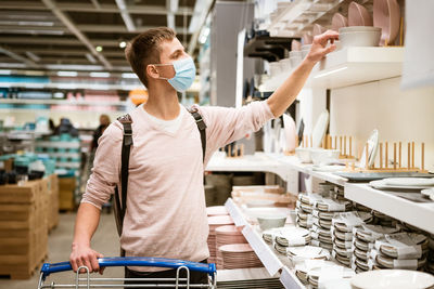 Young man chooses dishes in the store