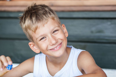 Portrait of smiling boy holding blue dice at home