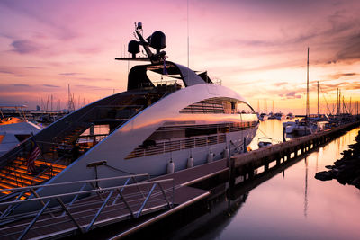 Ship moored at harbor against sky during sunset