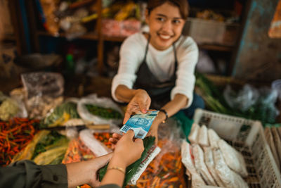 Portrait of young woman holding fish for sale at market