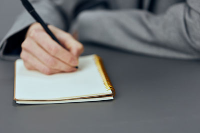 Midsection of man writing in book