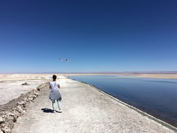 Rear view of woman standing on atacama desert against clear blue sky