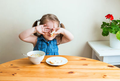 Cute girl eating food at table