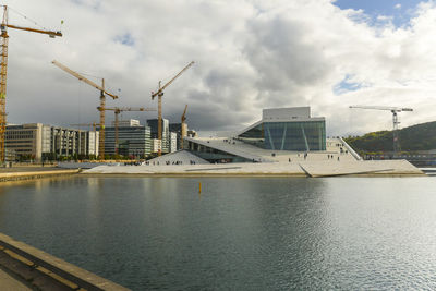 Buildings by river against sky