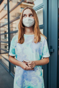 Portrait of beautiful young woman standing against wall