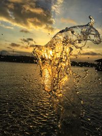 Close-up of water splashing against sky during sunset