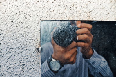 Close-up of man photographing while standing against mirror