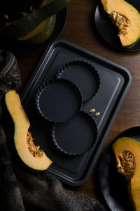 Pieces of sliced pumpkin on the dark table with dark dishes