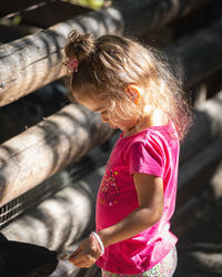 Cute girl feeding goat while standing outdoors