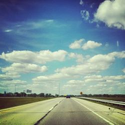 Road passing through country road against cloudy sky