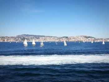 Sailboats in sea against clear blue sky