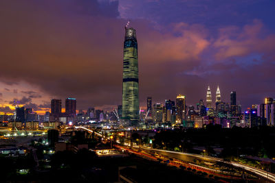 Illuminated modern buildings in city against sky at night