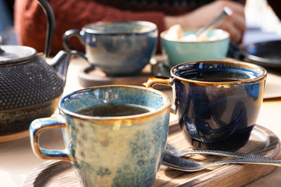 Brewing and serving tea. teapot poured green tea blue ceramic cup on wooden cafe table. two pottery