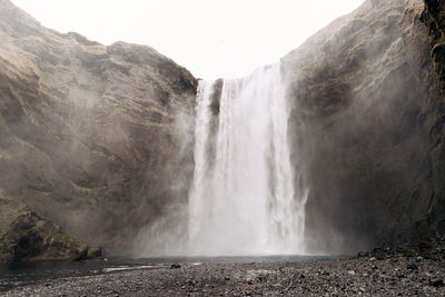 Scenic view of waterfall against rocky mountains