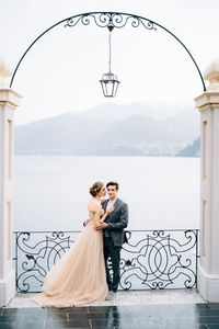 Couple holding umbrella by sea against sky