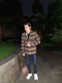 Portrait of young man looking away while standing on footpath