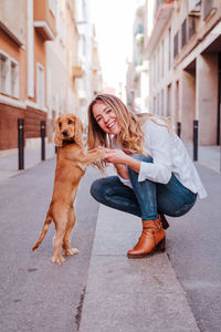 Full length portrait of woman with dog in city