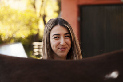 Young blonde woman with her brown horse enjoys a day on the farm.