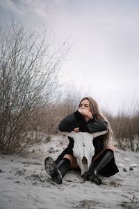 Woman sitting on sand on the beach in winter