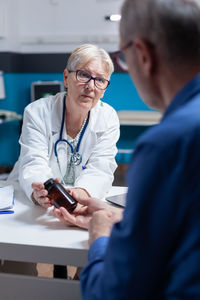 Doctor wearing mask prescribing medicine in hospital