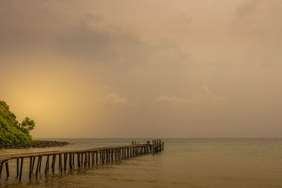 Pier over sea against sky during sunset