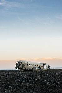 Abandoned airplane on land against sky during sunset