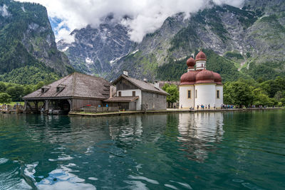 House by lake and mountains against sky