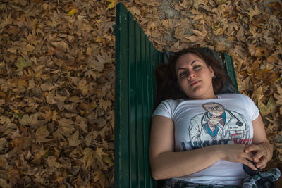 Portrait of a young woman lying down on autumn leaves