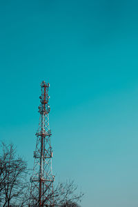 Low angle view of electricity pylon against clear blue sky