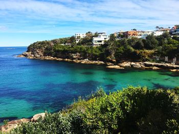 Scenic view of sea by buildings against sky