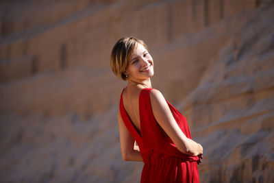 Young woman standing against red wall