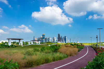 Road by buildings against sky