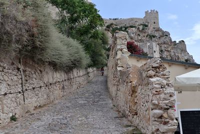 Stone wall by old building against sky