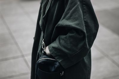 Midsection of woman wearing overcoat standing on footpath