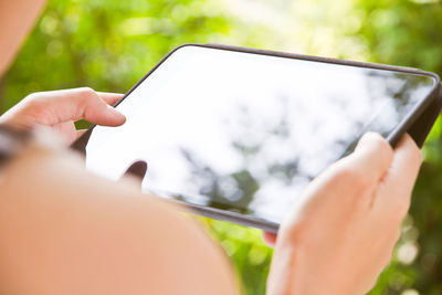Cropped hands of woman using digital tablet