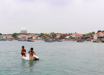 People enjoying in sea against sky