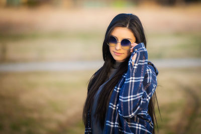 Portrait of young woman wearing sunglasses standing on field