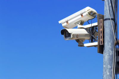 Low angle view of telephone pole against clear blue sky