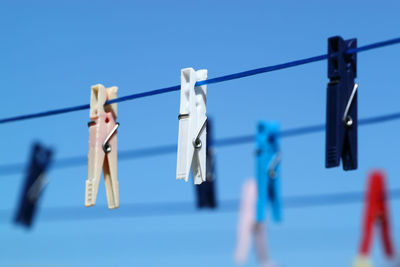Close-up of clothes hanging on rope against blue sky