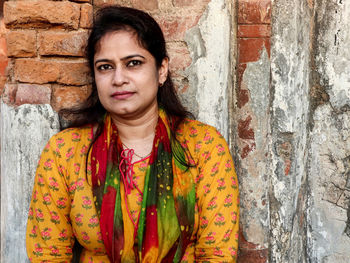 Woman in sunlight sitting in front of old building