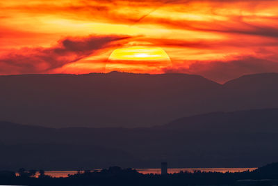 Scenic view of silhouette mountains against orange sky