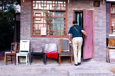 Rear view of man sitting on chair in city