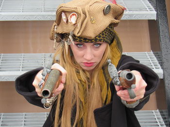 Portrait of woman holding guns while wearing pirate costume