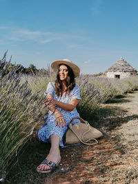 Portrait of beautiful happy young woman sitting in lavender field