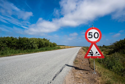 Road sign against sky during sunny day