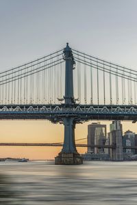 Bridge over river against sky in city